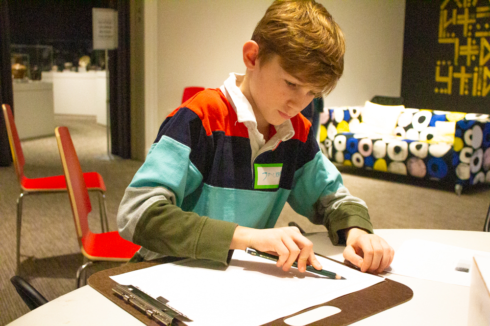 Image of boy drawing in gallery with sketchboard