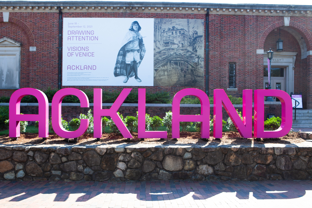Photograph of the front of the Ackland Art Museum showing a large fuchsia sign reading "ACKLAND"